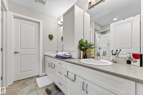 Dual white vanities with integrated sinks, ample storage cabinetry, and a full-width mirror - 85 165 Cy Becker Boulevard, Edmonton, AB - Indoor Photo Showing Bathroom
