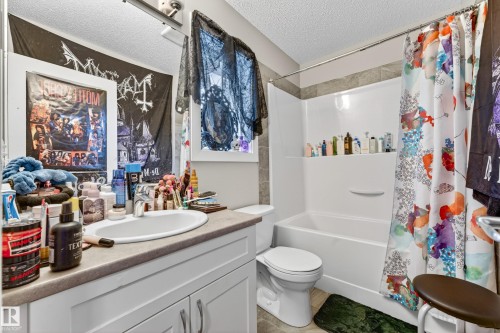 Bathroom featuring a single vanity with an integrated sink, a white bathtub with a shower surround, and a coordinating toilet - 85 165 Cy Becker Boulevard, Edmonton, AB - Indoor Photo Showing Bathroom