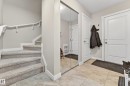 Entryway featuring light-toned tile flooring, a mirrored closet, and a staircase with carpeted treads and white handrails - 85 165 Cy Becker Boulevard, Edmonton, AB  - Indoor 