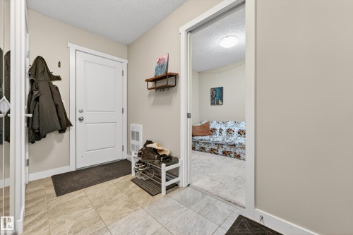 Entryway featuring tiled flooring, a white paneled door with brushed nickel hardware, and neutral wall tones - 85 165 Cy Becker Boulevard, Edmonton, AB - Indoor Photo Showing Other Room