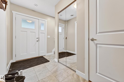 Entryway featuring a white paneled door with frosted glass insert, coordinating sidelight, and tile flooring - 85 165 Cy Becker Boulevard, Edmonton, AB - Indoor Photo Showing Other Room