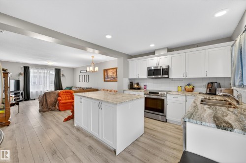 Kitchen featuring white shaker cabinetry, stainless steel appliances, a tile backsplash, and light-toned countertops - 85 165 Cy Becker Boulevard, Edmonton, AB - Indoor Photo Showing Kitchen