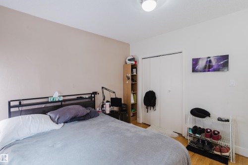 Bedroom featuring light wood-finish flooring, a built-in closet with bi-fold doors, and a ceiling-mounted light fixture - 11158 65 Street, Edmonton, AB 