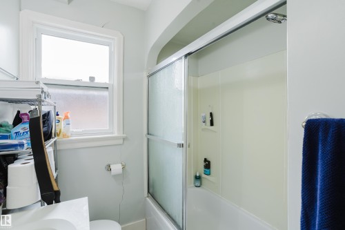 Tub and shower combination featuring a sliding glass enclosure and integrated wall-mounted shelving - 11158 65 Street, Edmonton, AB 