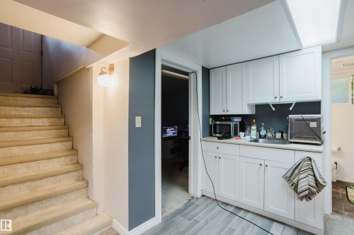 Functional kitchenette featuring white shaker-style cabinetry, a stainless steel sink, and light-toned countertops - 11158 65 Street, Edmonton, AB 