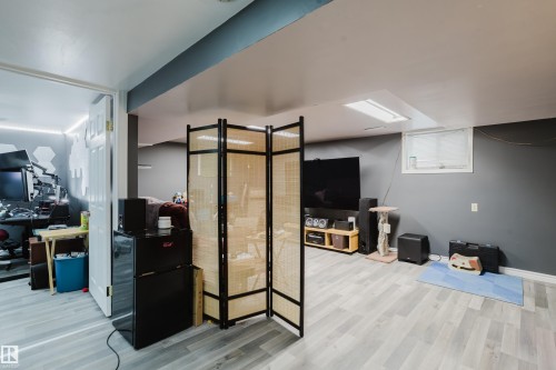 Finished lower level featuring light wood-finish flooring, recessed lighting, and a neutral color palette - 11158 65 Street, Edmonton, AB 