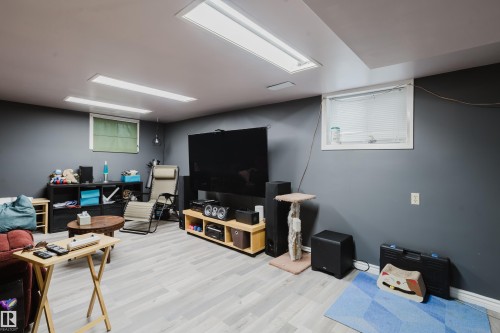 Spacious room featuring light wood-finish flooring, dark gray walls, and recessed lighting - 11158 65 Street, Edmonton, AB 