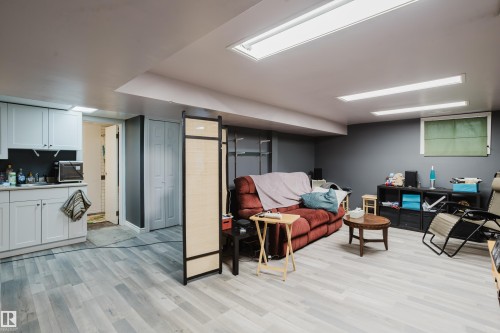 Spacious room featuring wood-finish flooring, recessed lighting, and a built-in wet bar with white cabinetry - 11158 65 Street, Edmonton, AB 