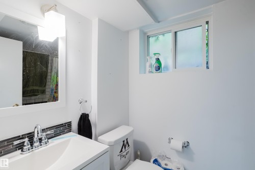 Bathroom vanity featuring an integrated rectangular sink, chrome faucet, and a mosaic tile backsplash - 11158 65 Street, Edmonton, AB 