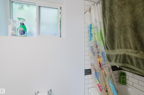 White subway tile shower surround with dark accent tile and a built-in tub - 11158 65 Street, Edmonton, AB 
