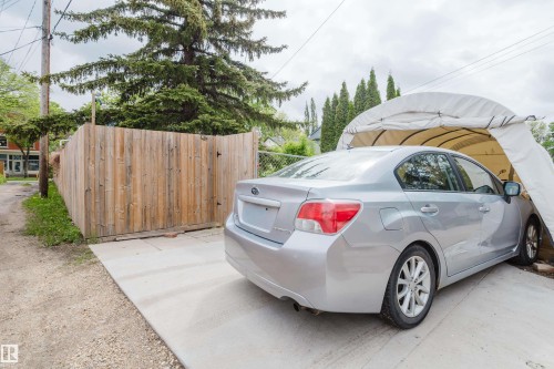 Paved concrete driveway with a wood privacy fence and mature trees - 11158 65 Street, Edmonton, AB 