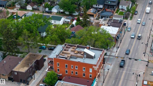 Multi-story brick building featuring multiple windows and a rooftop patio space with visible seating - 11158 65 Street, Edmonton, AB 