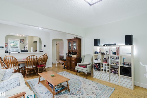 Living area featuring wood-finish flooring, a tray ceiling light fixture, and an arched doorway - 11158 65 Street, Edmonton, AB 
