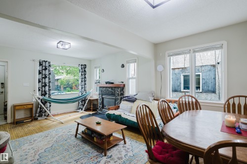 Spacious living area featuring wood-finish flooring, a decorative fireplace with stone surround, and multiple windows - 11158 65 Street, Edmonton, AB 
