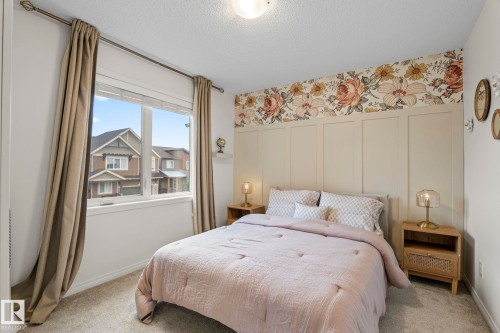 Bedroom featuring a decorative accent wall with floral wallpaper and board and batten detailing - 20227 17Ave, Edmonton, AB 