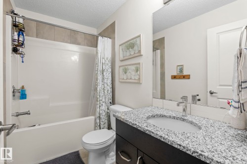 Bathroom featuring a white tub and shower combination with light-toned wall tiling - 20227 17Ave, Edmonton, AB 
