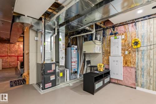 Utility area featuring a furnace, water heater, exposed ductwork, and electrical panels - 20227 17Ave, Edmonton, AB 