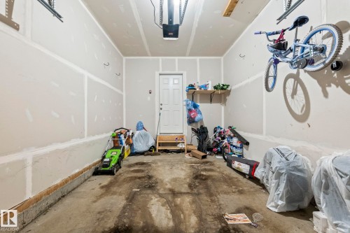 Spacious garage featuring a concrete floor, light gray walls, and an overhead garage door opener - 20227 17Ave, Edmonton, AB 