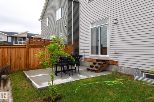 Concrete patio space with a wooden privacy fence and a small tree - 20227 17Ave, Edmonton, AB 