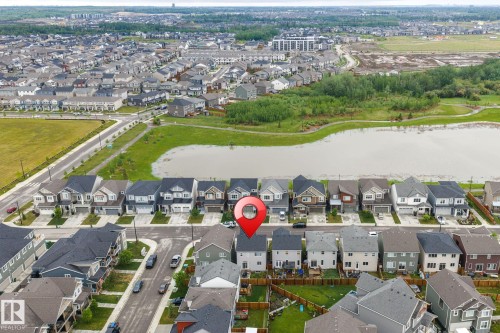 Aerial capture of a residential community featuring a prominent pond and green spaces - 20227 17Ave, Edmonton, AB 