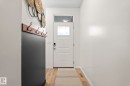 Entryway featuring wood-finish flooring and a white paneled door with frosted glass and a transom window - 20227 17Ave, Edmonton, AB 