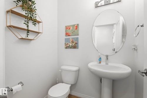 Pedestal sink with chrome faucet, an oval mirror, and chrome vanity lighting - 20227 17Ave, Edmonton, AB 