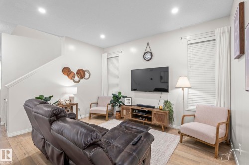 Spacious living area featuring wood-finish flooring, recessed lighting, and white window blinds - 20227 17Ave, Edmonton, AB 