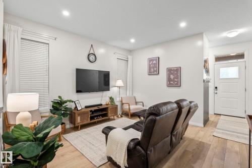 Recessed lighting illuminates this living space featuring light wood-finish flooring and neutral wall tones - 20227 17Ave, Edmonton, AB 
