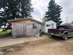 Wood-sided outbuilding with single pane window and double wooden doors - 