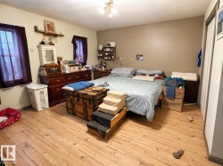 Bedroom featuring light wood-finish flooring, two windows, and neutral-toned walls - 