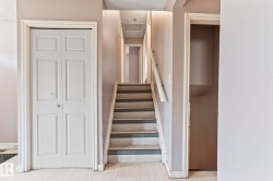Staircase featuring wood-finish treads and risers, complemented by a white handrail - 