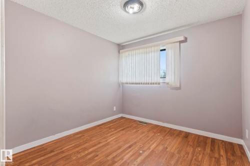 Room featuring wood-finish flooring, a window with vertical blinds, and a flush-mount ceiling light fixture - 2045 46St, Edmonton, AB 