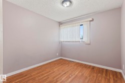 Room featuring wood-finish flooring, a window with vertical blinds, and a flush-mount ceiling light fixture - 