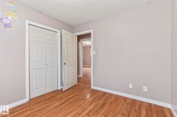 Neutral gray wall paint with white trim, wood-finish flooring, and white paneled doors - 