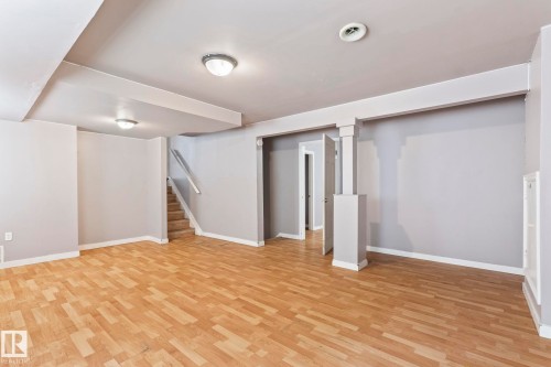 Spacious room featuring light wood-finish flooring, recessed lighting, and a neutral wall palette - 2045 46St, Edmonton, AB 
