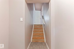 Staircase with wood-finish treads, a white handrail, and a paneled door at the landing - 