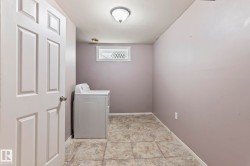 Utility space featuring large format square floor tiles, a window with decorative grates, and a flush mount ceiling light fixture - 