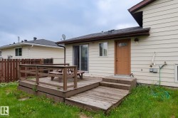 Rear exterior featuring a wooden deck with railing, sliding glass door, and an additional exterior door with a decorative glass insert - 