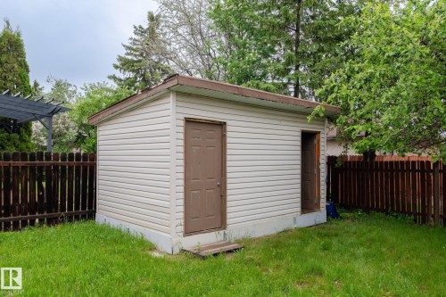 Detached storage shed with two brown panel doors, light-colored siding, and a brown trim roofline - 2045 46St, Edmonton, AB 