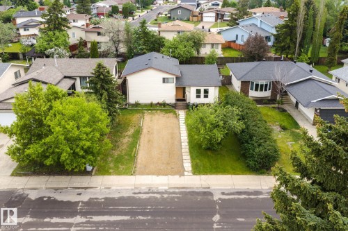 Split-level residence featuring a dark shingle roof, light-colored siding, and a prominent front entry - 2045 46St, Edmonton, AB 