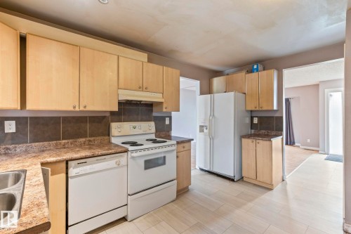 Kitchen featuring light wood-finish cabinetry, a white electric range, and a white dishwasher - 2045 46St, Edmonton, AB 