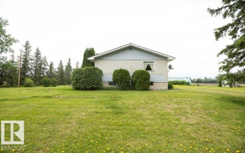 Exterior featuring a light-colored stucco finish with light blue siding, a peaked roof, and a single visible window with drapes - 2021 Twp Rd 604, Rural Westlock County, AB 