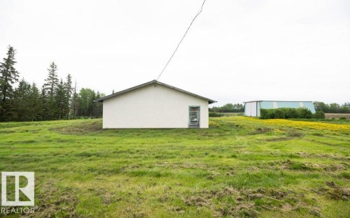 White stucco building with a gable roof, surrounded by expansive green grounds - 2021 Twp Rd 604, Rural Westlock County, AB 