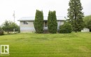 Single-story residence featuring a light-colored metal roof, pale siding, and a partial exposed foundation - 2021 Twp Rd 604, Rural Westlock County, AB 