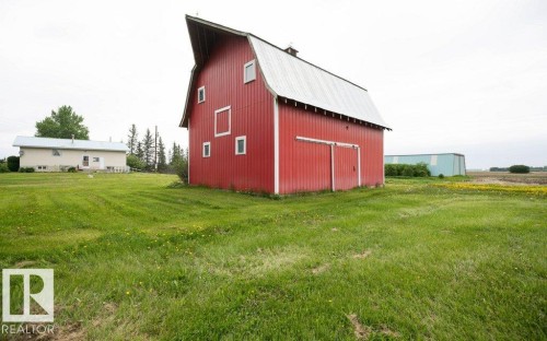 Red barn with a gambrel roof and white trim, featuring multiple windows and large sliding doors - 2021 Twp Rd 604, Rural Westlock County, AB 