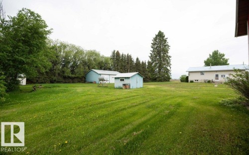 Expansive outdoor space featuring a large grassy area, mature trees, and multiple outbuildings - 2021 Twp Rd 604, Rural Westlock County, AB 