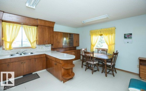 Spacious kitchen and dining area featuring extensive wood cabinetry, a double basin sink, and ample countertop space - 2021 Twp Rd 604, Rural Westlock County, AB 