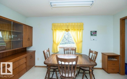 Dining area featuring a wood-finish built-in hutch with glass-front display cabinets, a window with natural light, and overhead fluorescent lighting - 2021 Twp Rd 604, Rural Westlock County, AB 