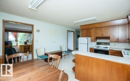 Kitchen and dining area featuring wood-finish cabinetry, a white electric range, and a white refrigerator - 2021 Twp Rd 604, Rural Westlock County, AB 