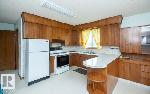 Kitchen featuring wood-finish cabinetry, white appliances, and a U-shaped countertop - 2021 Twp Rd 604, Rural Westlock County, AB 